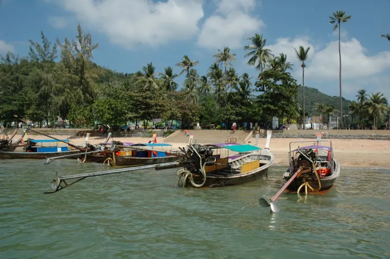 Uma fila de barcos longtail encostados à margem em Ao Nang, Krabi